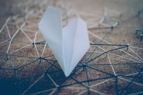 White paper plane over the threads linking the nails. Entities connected.  Stock Photos