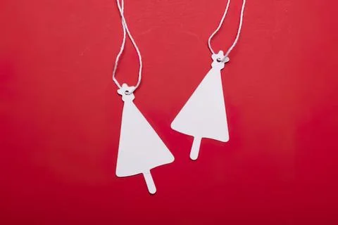White paper popsicle and tree-shaped tags hanging on red background Stock Photos