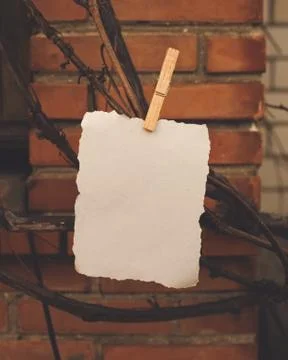 White paper sheet pinned on a rustic rope in front of red orange brick wall and Stock Photos