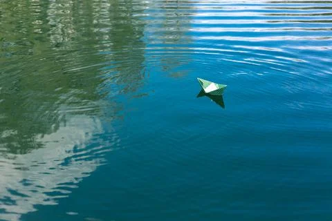 White paper skiffs float on water. Origami. Stock Photos