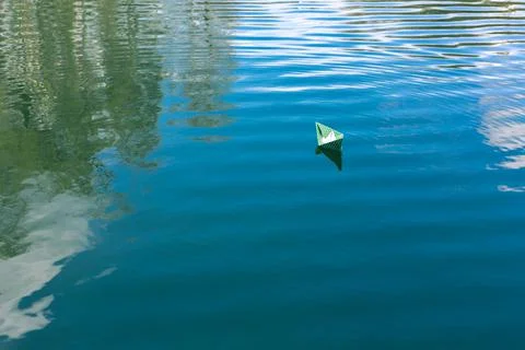 White paper skiffs float on water. Origami. Stock Photos