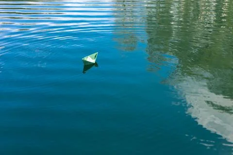 White paper skiffs float on water. Origami. Stock Photos