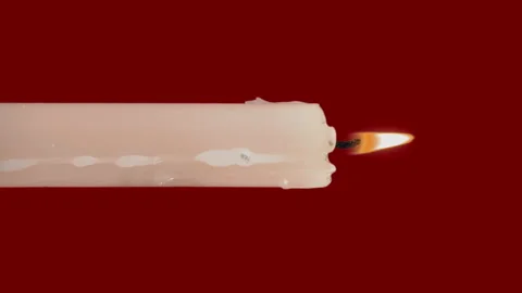 White Paraffin Candle with Yellow Tints Burns on a Red Background Video stock 211110992