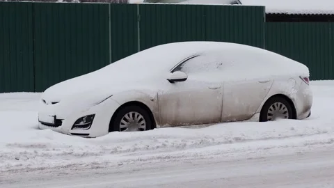 A white passenger car parked under a cap of snow in the city in winter, slow Stock Footage 291775543
