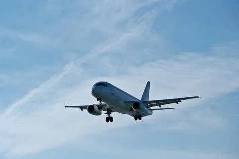 White passenger plane on final approach on a sunny day with blue sky Stock Photos