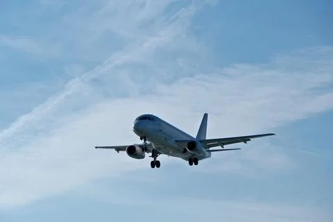 White passenger plane on final approach on a sunny day with blue sky Stock Photos