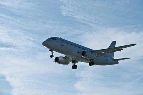 White passenger plane on final approach on a sunny day with blue sky Stock Photos