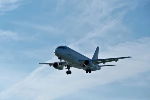 White passenger plane on final approach on a sunny day with blue sky Stock Photos