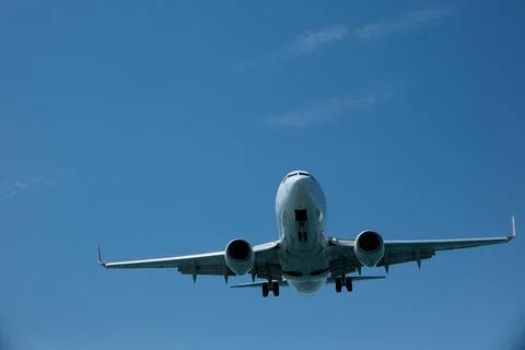 White passenger plane on final approach for landing against a blue sky Stock Photos