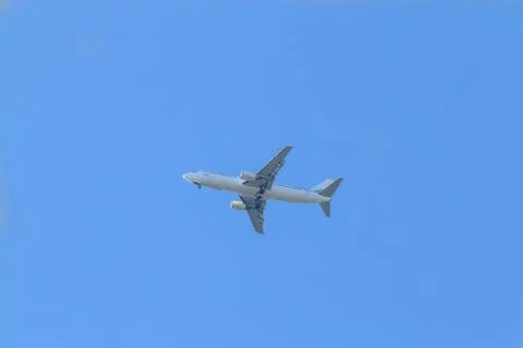 White passenger plane flies highly in the sky on a bright Sunny day without.. Stock Photos