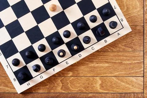 White pawn attacking black figures on the chessboard after the first move Stock Photos