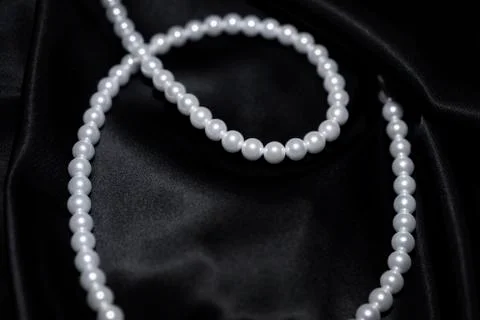 White pearl necklace on a black silk Stock Photos