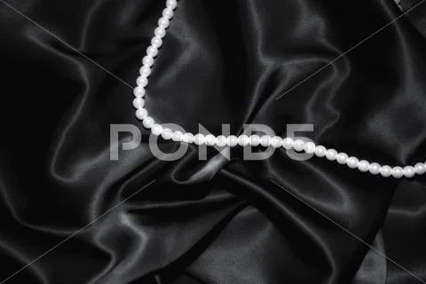 White pearl necklace on a black silk close up Stock Photos