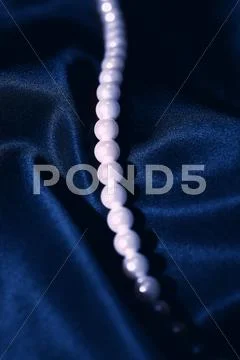 White pearl necklace on a dark blue silk Stock Photos
