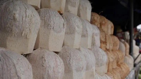 White peeled coconuts are displayed on a vendor table, ready to be opened and Stock Footage 313485841