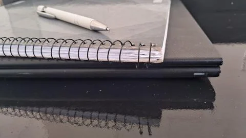 White pen resting on a spiral notebook atop black laptop Stock Photos