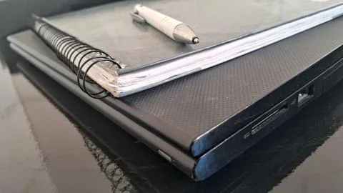 White pen resting on a spiral notebook atop black laptop Stock Photos