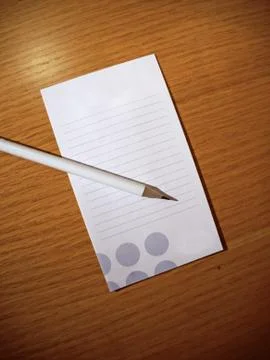 White pencil and notebook sheet lying on a wooden table Stock Photos