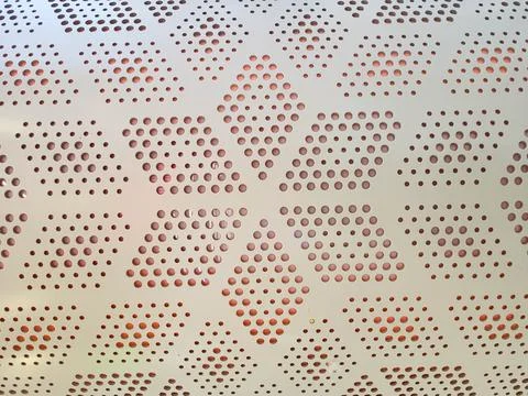 White perforated metal panel with a repeating pattern. Stock Photos