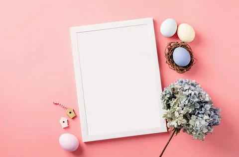 White photo frame with easter decorations flat lay on pink background Stockfoto's