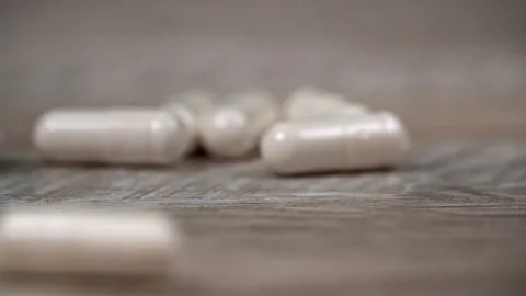 White Pill Capsules Fall to the Surface in Slow Mo Stock Footage 219778114