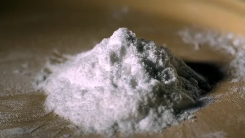White pill falling on a small heap of cocaine powder in slow motion Stock Footage