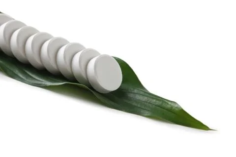 White pill lying on a green leaf Stock Photos