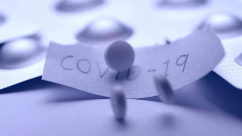 White pill tablet falling into paper with the text COVID-19 in slow motion Stock-Footage 125840640