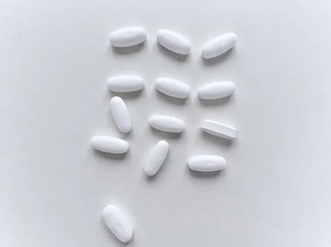 A white pill is on a white surface Stock Photos