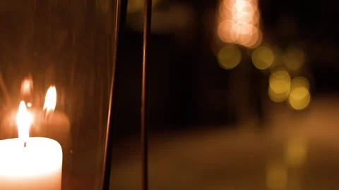 White Pillar Candle Burning Inside Glass Hurricane Lantern with Bokeh Background Stock Footage 325692524