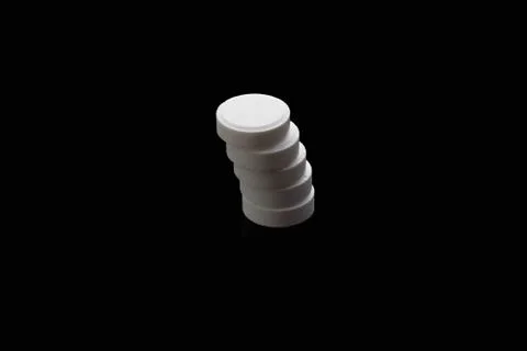 White pills arranged to stack isolated on black background. Medical concept. Stock Photos