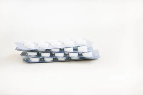 White pills in blisters on the white background Stock Photos