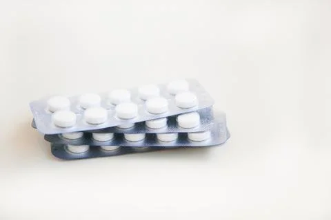 White pills in blisters on the white background Stock Photos