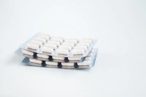 White pills in blisters on the white background Stock Photos
