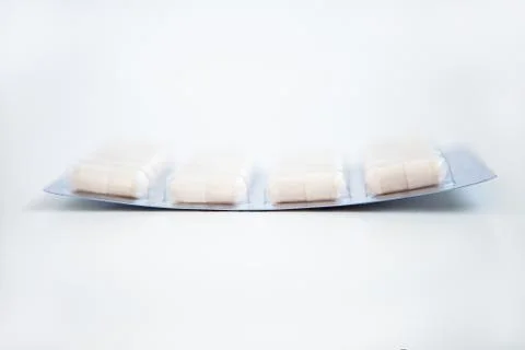 White pills in blisters on the white background Stock Photos