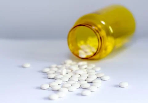 White pills with bottle in background Stock Photos