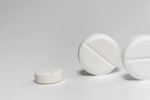 White pills close-up on a light background. Stock Photos