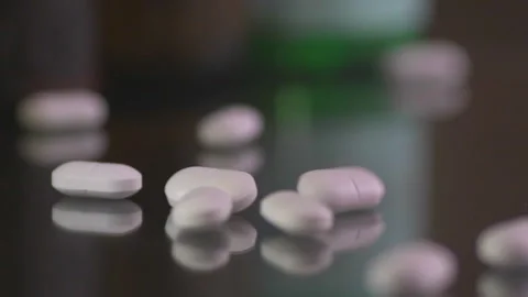 White pills dropping on a table surface, close up Stock Footage 255388911