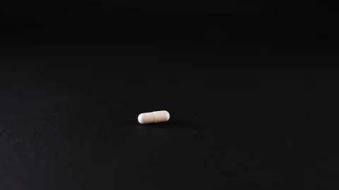 White pills fall on a black background Stock Footage 127180192