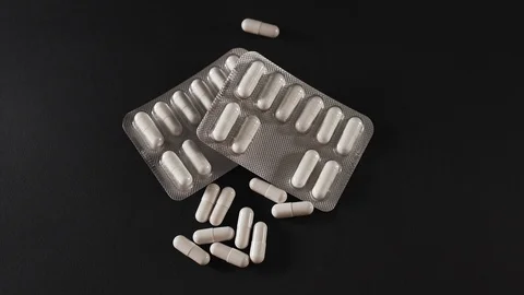 White pills fall on a black background Stock Footage 127180605
