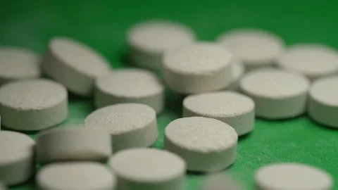 White pills fall down onto green surface extreme close view Stock Footage 124669511