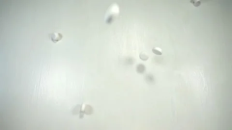 White pills fall in slow motion on a white Stock Footage 140758717