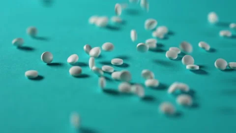 White pills falling down onto a blue background 4K 30fps 스톡 동영상 228886497