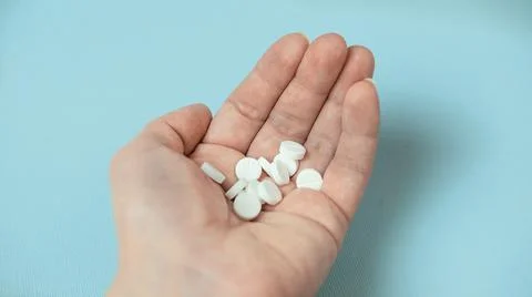 White pills in hand on a blue background , the concept of Christmas and medicine Stock Photos
