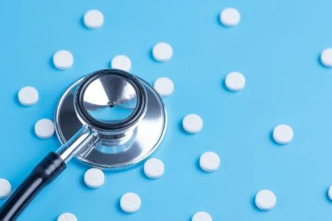 White pills or tablets and stethoscope on blue background Stock-Fotos