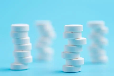 White pills or tablets stacked on each other in different positions on blue b Stock Photos