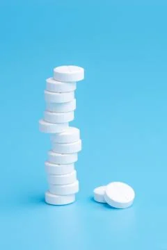 White pills or tablets stacked on each other in different positions on blue b Stock Photos