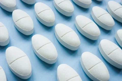 White pills pattern symbolizing daily medication routine. Stock Photos