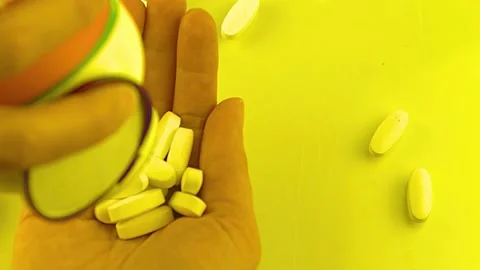 White pills poured into hand against bright yellow surface background Stock-Footage 341969944
