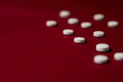 White pills on red background. Stock Photos